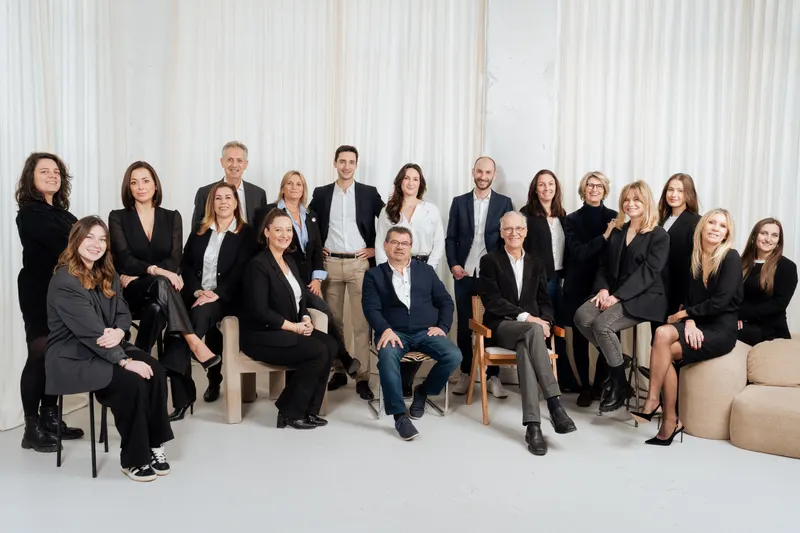 Photo de groupe de dix-sept collaborateurs, assis et debout devant un rideau clair