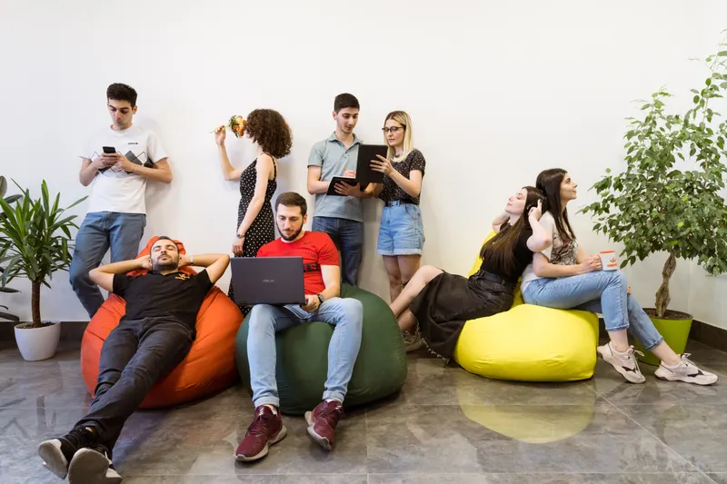 Équipe détendue dans un espace de travail, certains installés sur des poufs colorés