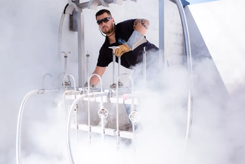 Opérateur dans un nuage de vapeur froide, vannes en inox au premier plan, regard vers l’objectif